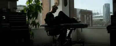 Andrew Stopay tattooing a client by the window of his studio overlooking Vancouver
