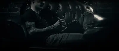 Andrew Stopay sketching a tattoo design on a tablet on a leather sofa