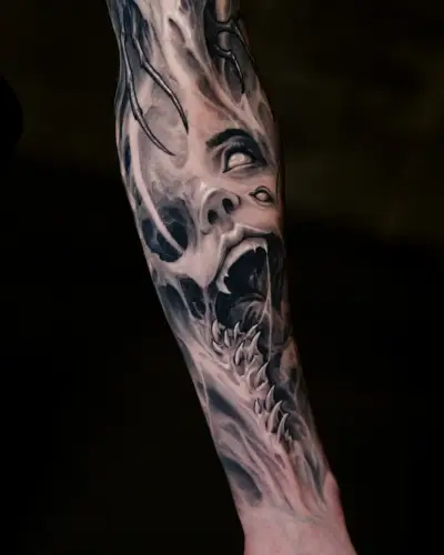 Bio-horror forearm tattoo by Andrew Stopay: a screaming face emerging from biomechanical bone and spine structures